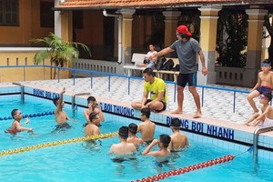 運動員梁玉維正在教孤兒學游泳。