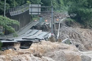 日本九州熊本縣蘆北町球磨川旁一條道路，因河水暴漲淘空路基而中斷。（圖源：AFP）