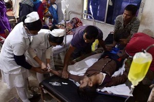 醫護人員正在搶救飲用假酒的中毒者。（圖源：AFP）