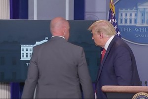 一名特勤人員走到台前與特朗普短暫交談後，護送特朗普離開。（圖源：視頻截圖）