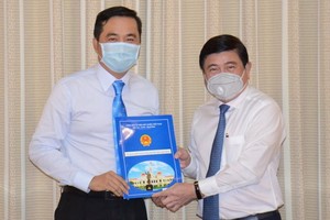 新任市工商廳長裴佐黃宇（左）從市人委會主席阮成鋒手中接過人事委任《決定》。（圖源：芳陲）