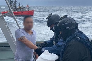 全副武裝的執法人員在浪高3.5米的惡劣環境下在海上突襲小船，逮捕了3人。（圖源：Getty Images）