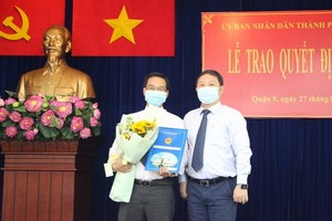 新任第五郡人委會副主席阮春忠（左）接領人事委任《決定》時與市人委會副主席楊英德合照。（圖源：梅花）