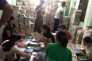 年輕人正在把剛收到的書籍分類，然後疊成一疊疊的。