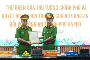 公安部副部長黎貴王（右）向河內市公安廳頒授政府總理簽發的表彰信及獎狀。（圖源：首都安寧報）