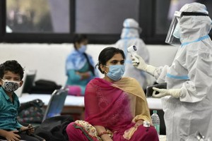 印度衛生部：印度新冠累計死亡病例於3日突破10萬例。圖為防疫人員在給一名婦女測量體溫。（圖源：互聯網）