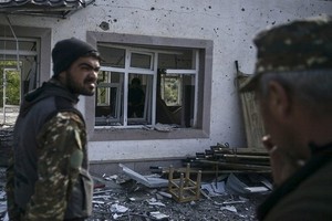 圖為亞美尼亞士兵站在被部分摧毀的軍事醫院建筑前。（圖源：AFP）