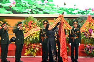國會主席阮氏金銀為《人民軍隊報》傳統旗幟上佩掛三等獨立勳章。（圖源：前鋒報）