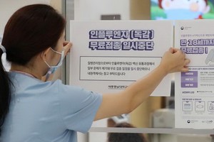 韓國世宗一間醫院的職員正在醫院入口處張貼告示，提醒民眾流感疫苗接種計劃暫停。 （圖源：路透社）