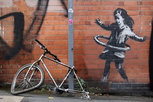 英國知名塗鴉藝術家班克西（Banksy）最新作品，描繪一名小女孩把腳踏車輪胎當呼拉圈搖。（圖源：路透社）