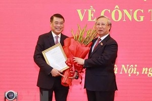 新任黨中央辦公廳主任黎明興（左）從黨中央書記處常務書記陳國旺手中接過人事委任《決定》。（圖源：越通社）