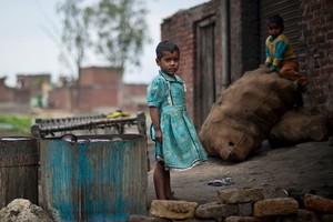 印度北方邦的貧民窟，兒童在一家金屬拋光工廠外玩耍。（圖源：聯合國）