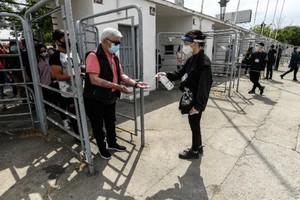 10月25日，在智利首都聖地亞哥一處投票站，一位老人在入口給手消毒。 智利25日舉行全民公投，選民們投票贊成成立“制憲會議”制定新憲法。（圖源：新華社）