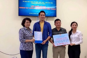 阮飛雄歌星與平西市場越華商販將善款交給市越南祖國陣線委員會領導。