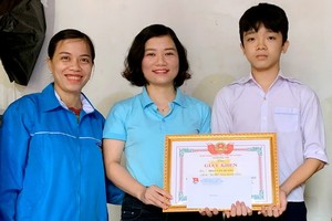 見義勇為的初中生潘文光（右一）從共青團河靖省德壽縣縣委書記黎氏玄莊手中接過獎狀。（圖源：德雄）