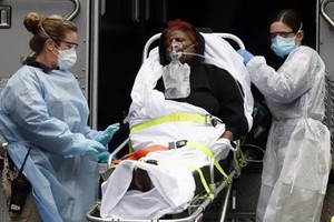 圖為紐約的一名新冠肺炎女患者獲送上救護車。（圖源：路透社）