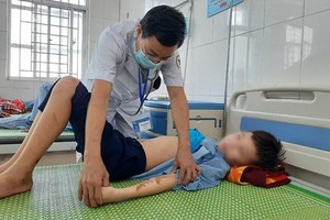 北寧省安豐縣醫療中心的一名醫生在為T.Q.D病童檢查傷勢。（圖源：銀英）