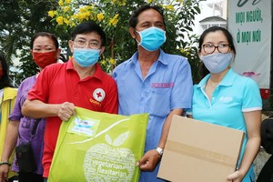 第五郡紅十字會主席黎勛峰（左）與「Habitat」項目管理人胡氏梅英（右）向貧困戶贈送禮物。