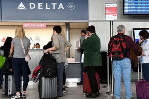 乘客在達美航空櫃檯辦理登機手續。（圖源：Getty Images）
