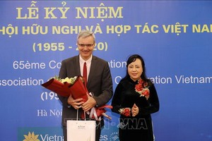 越-法合作與友協主任阮氏金進（右）向法國駐越南大使尼古拉斯‧華納贈送鮮花。（圖源：越通社）