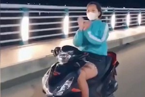 女騎士不但放手騎車，還在高速中揮舞雙手模仿扇子舞姿態，模樣相當危險。（圖源：視頻截圖） 