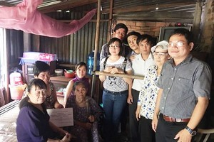 阮復興教師（右一）帶領學生到一個貧困家庭送禮品。