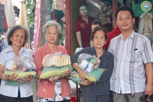 富山五行廟慈善組組長鄒國榮（右一）向貧困者派發賑濟品。