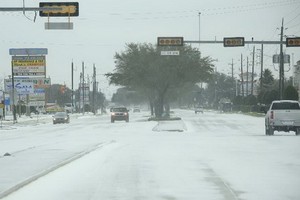 2月15日，在美國得克薩斯州休斯敦，車輛在積雪的道路上行駛。（圖源：新華社）