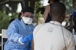 環形疫苗接種小組的一名成員正在博索洛村為一名男子接種疫苗。 （圖源：WHO）