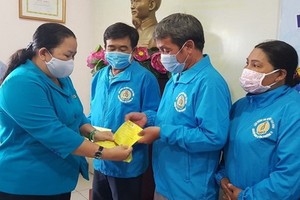 市勞動聯團副主席黎氏金翠（左）向新平郡網約“摩的”業團會員頒發意外保險證。（圖源：德龍）