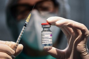 圖為醫務人員拿著一個注射器和一小瓶 AstraZeneca 新冠病毒疫苗。（圖源：AFP）