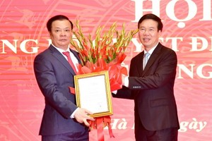 新任河內市市委書記丁進勇（左）從黨中央書記處常務書記武文賞手中接過人事委任《決定》和祝賀鮮花。（圖源：VGP）