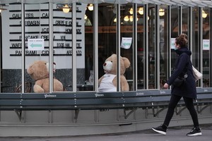 一名女子走過法國巴黎街頭一家關門的餐館。（圖源：新華社）