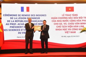 法國駐越南特命全權大使（左）向周文明教授（右）頒授北斗星勳章。（圖源：阮懷）