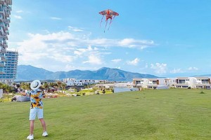 遊客在度假區海灘旁的草坪上放風箏。