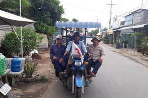 陳文懷（右）與三輪車隊成員們在去砍柴的途中。