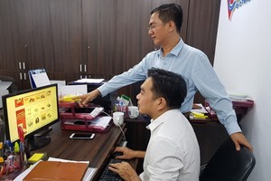 陳輝強（站）與同事一起查看在“堤岸線上集市”上商品。