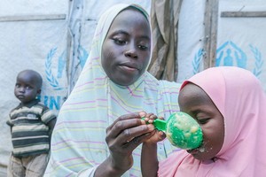 加利福尼亞州的一位母親用從世界糧食計劃署處的糧食點領取的穀類食品為她的孩子準備食物。（圖源：聯合國）