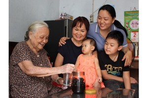 黃振英-謝珍（左一、二）母女一家四代人高興地圍著一瓶陳年鹹金桔。