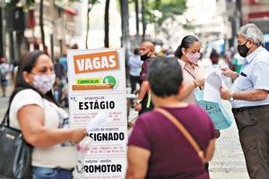 受疫情影響，全球失業率暴增。圖為巴西民眾查看職位列表公告板，一名女性將簡歷交給了招聘機構工作人員。（圖源：路透社）