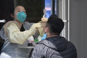 在檢測室內不用穿防護服的醫護人員為民眾採樣檢測。