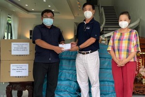 華人熱心人士鄧栢榮、區美莉伉儷(右)向第十一郡第一坊領導移交支持防疫物資。