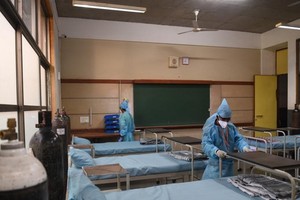 印度古吉拉突邦艾哈默德巴德郊區學校已被改建為新冠護理中心管理員在安排床位。（圖源：互聯網）