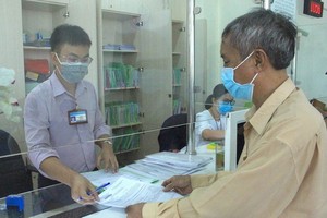 一名平新郡公務員在為當地居民解決行政手續。（圖源：黎叉）