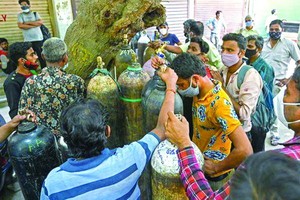 新德里居民攜氧氣鋼瓶排隊等待為居家隔離的新冠患者充醫用氧氣。（圖源：互聯網）