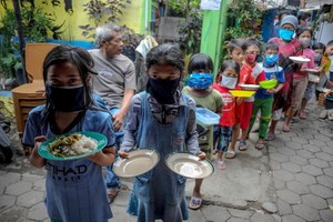 圖為去年4月10日，印尼西爪哇省萬隆市的居民戴著口罩，拿著盤子排隊領取免費食物。 （圖源：路透社）