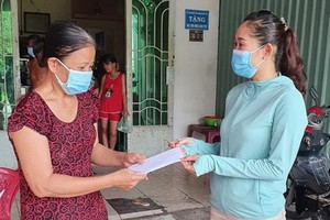 平新郡新造坊人委會副主席阮氏雪絨（右）把補助金交給當地受疫情影響的自由勞工。