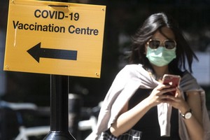 7月16日，行人走過英國倫敦街頭一個疫苗接種點的標誌牌。（圖源：新華社）