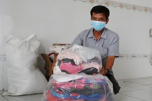 黎老師裹著贈送給清貧學生的書包、背包、衣服。