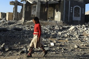 一名女童走過也門薩那的廢墟。（圖源：聯合國）